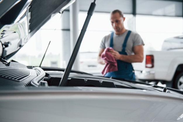 Monteur staat bij een auto met motorklep open